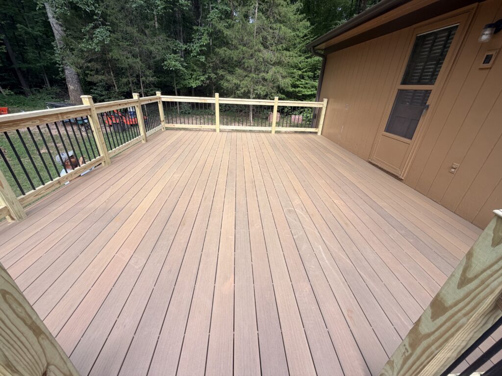 Deck beside a house with wood rail posts and black balusters