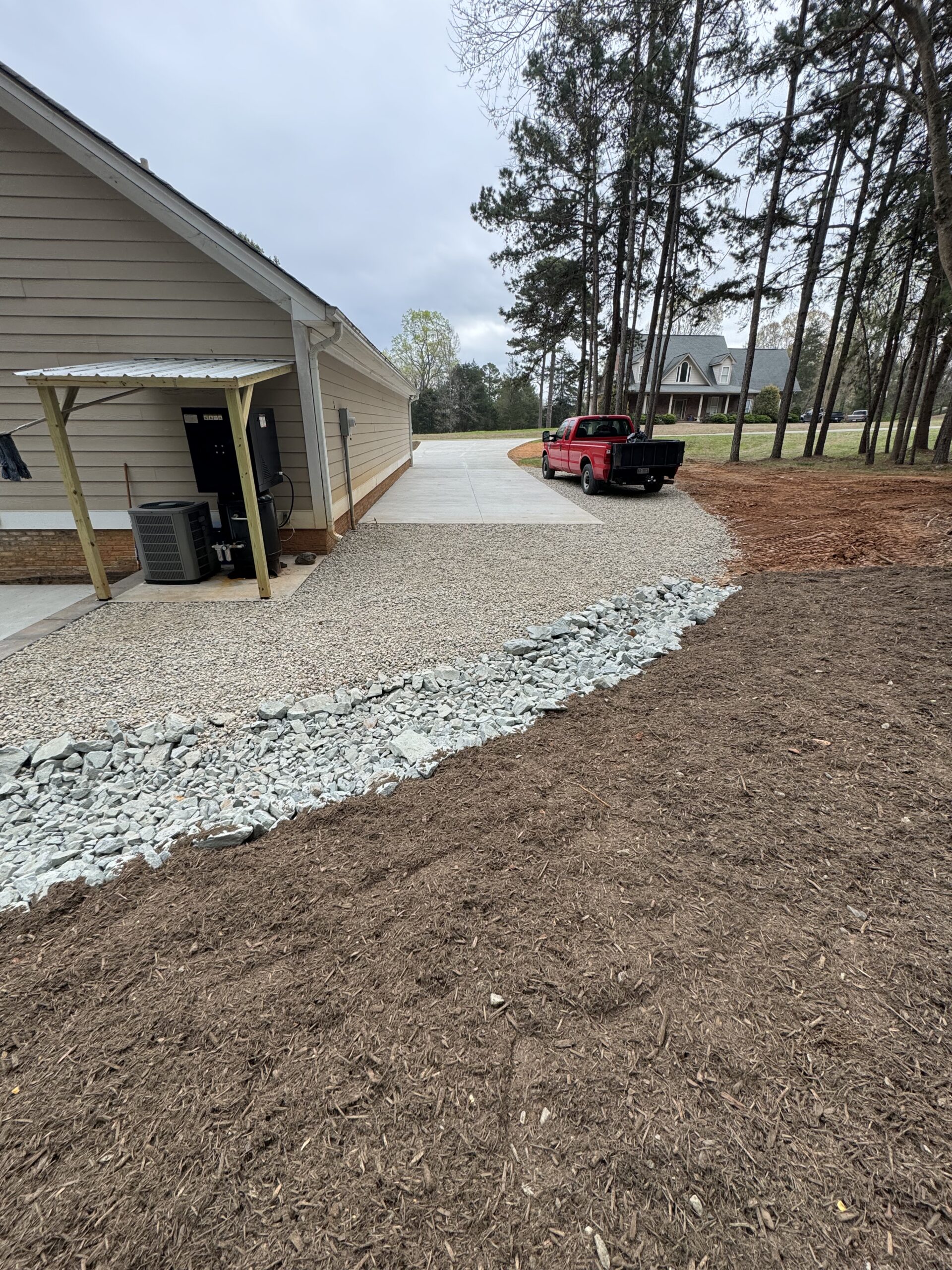Rock-lined drainage channel beside a gravel drive and graded yard