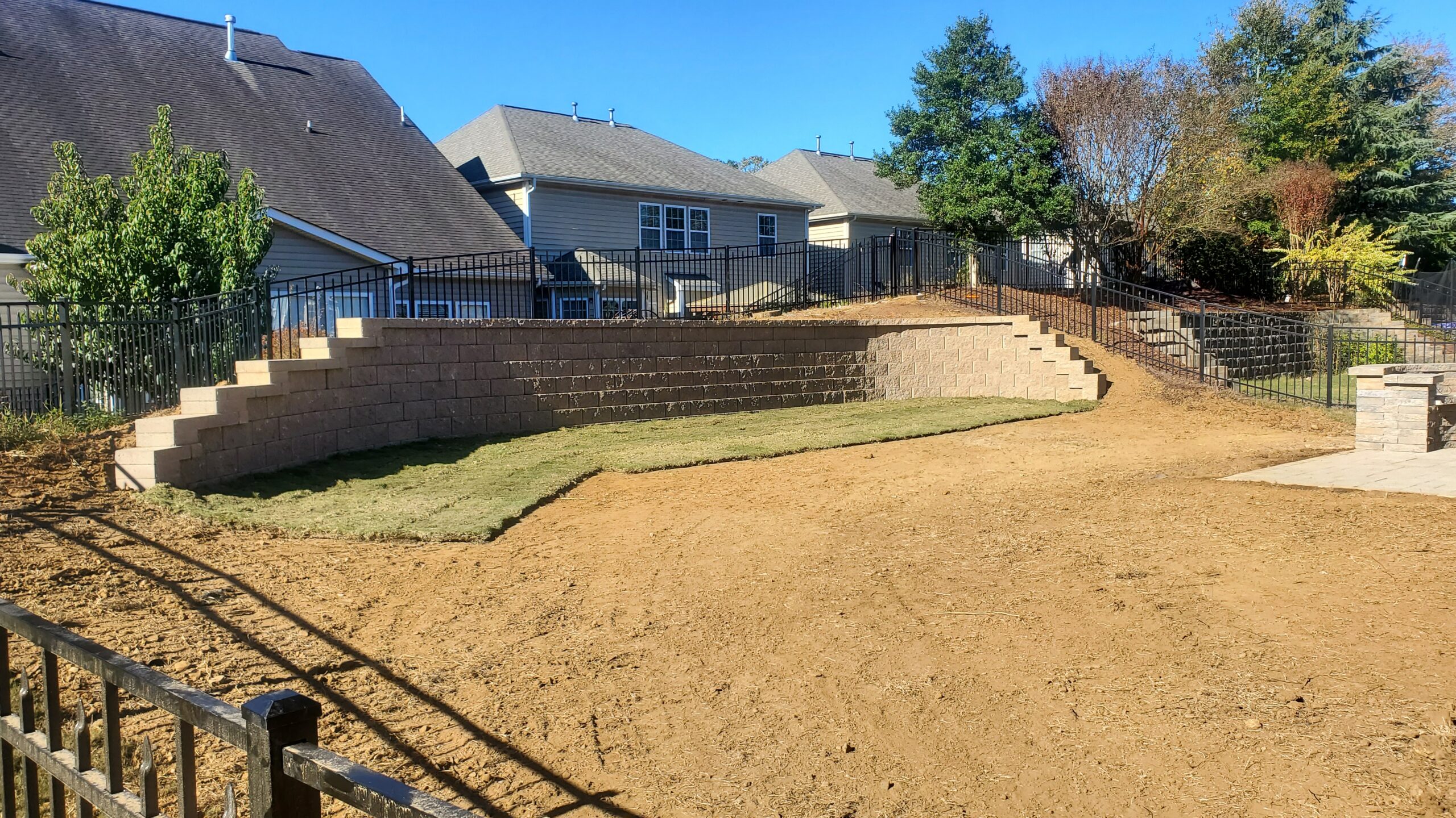 Block retaining wall shaping a lawn beside a house