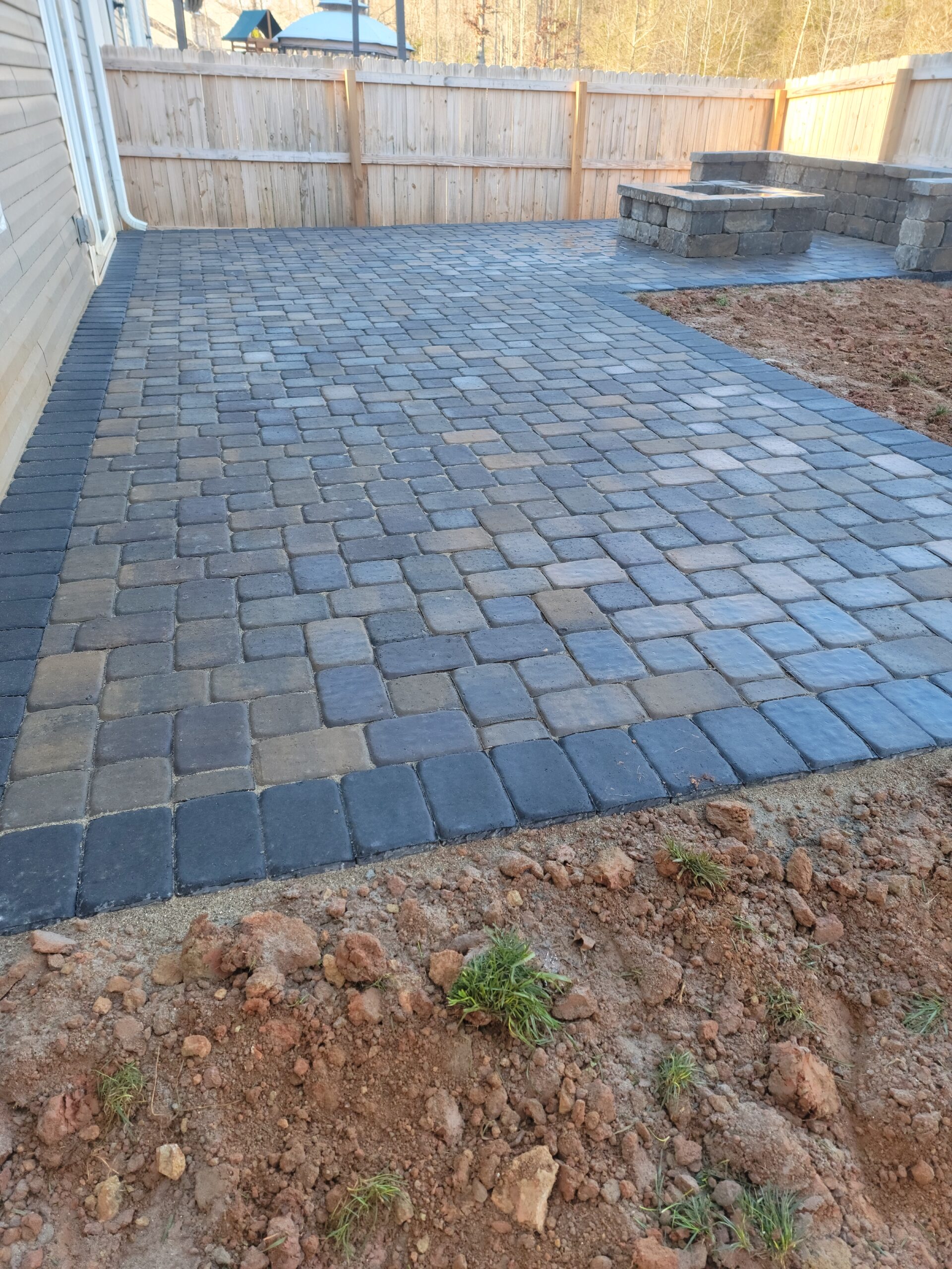 Gray paver patio with a contrasting border beside a home