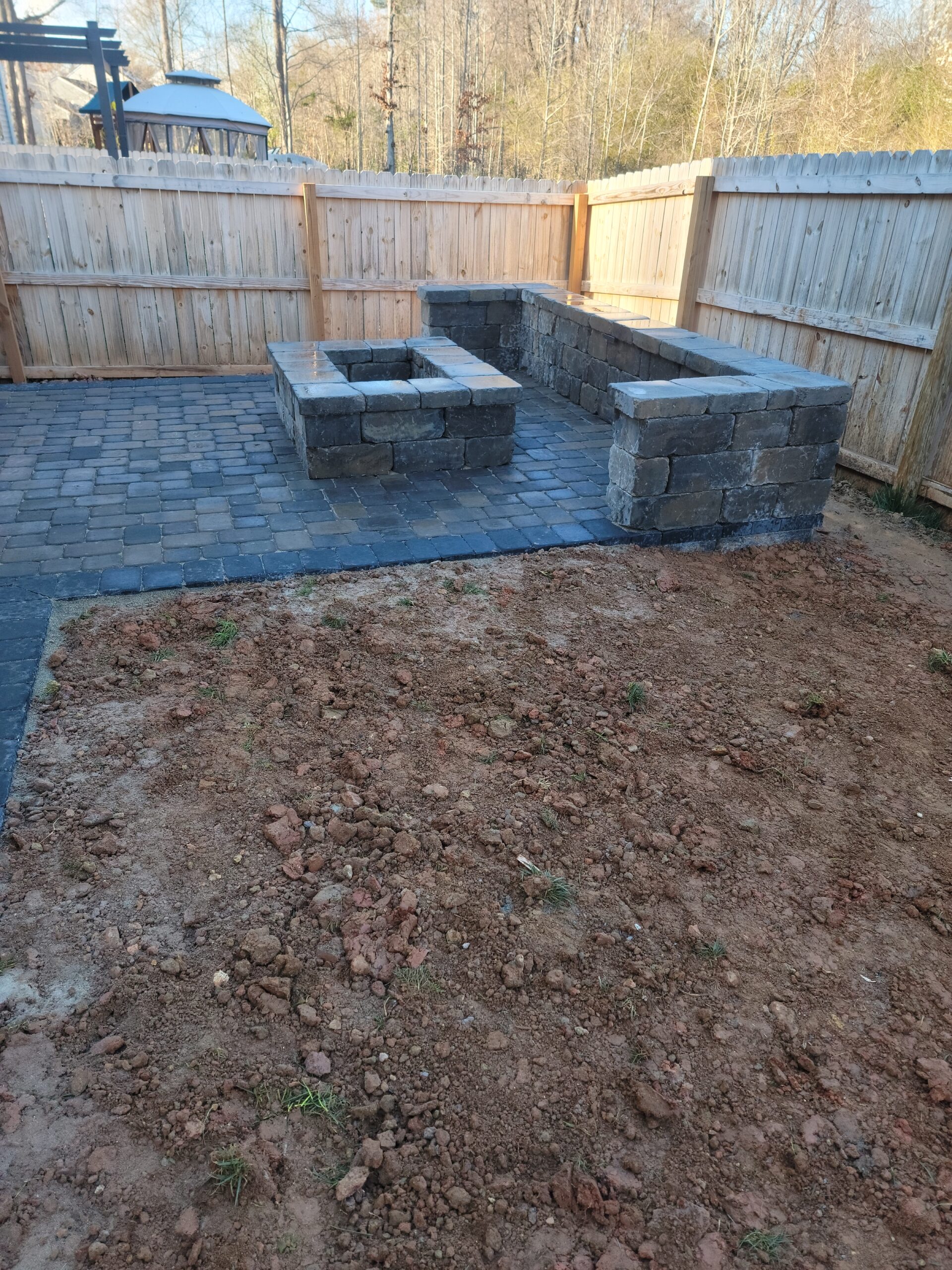 Paver patio with a square fire pit and block seating wall