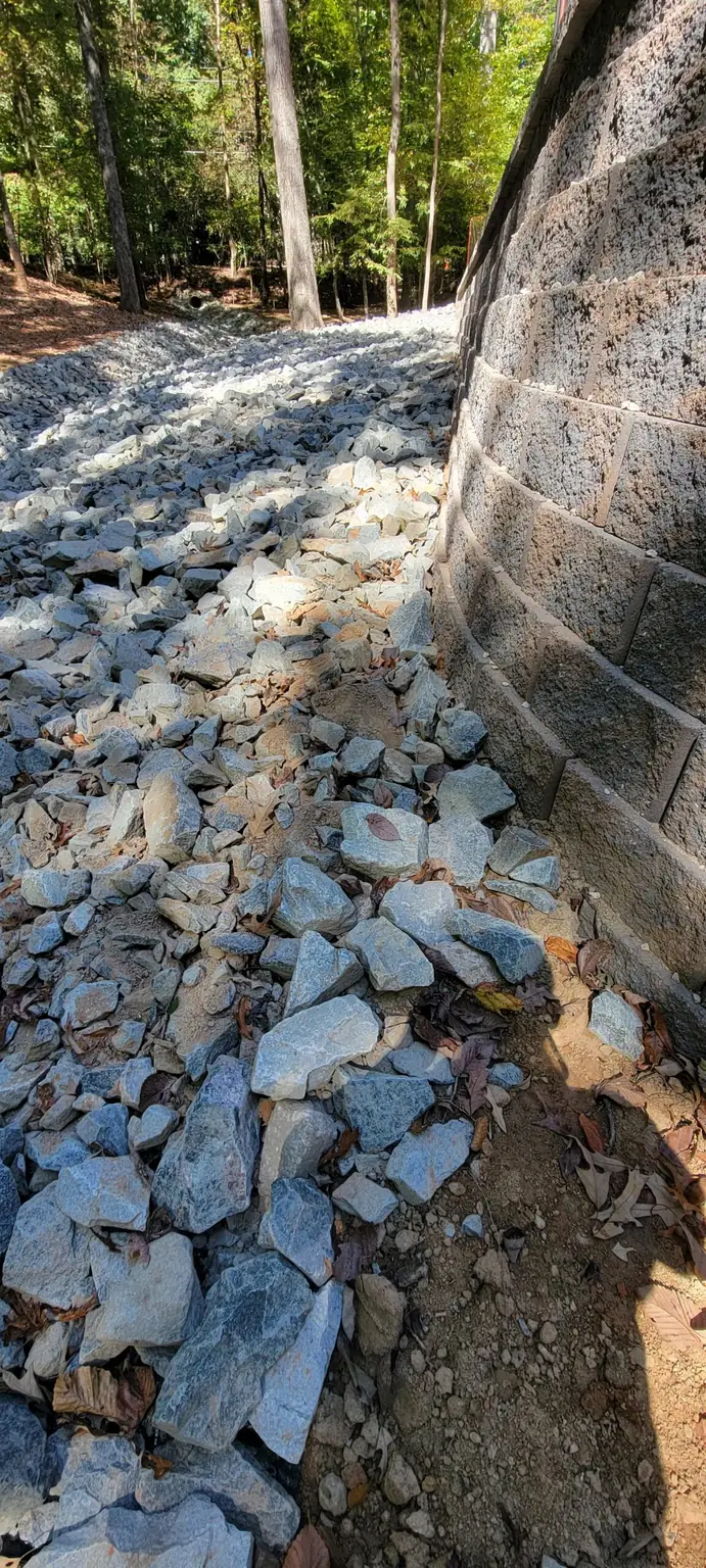 Stone-lined drainage area beside a block wall